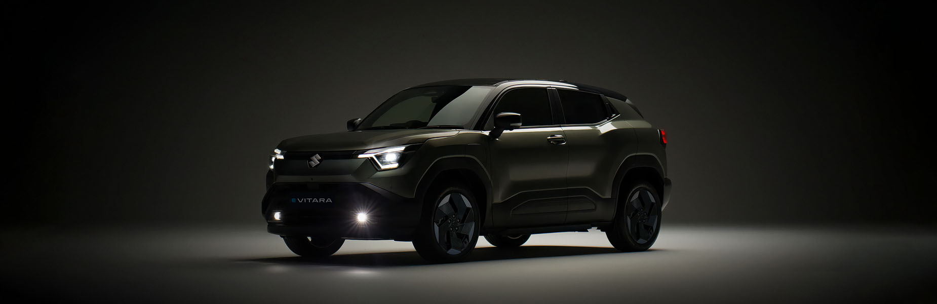 A darkened Suzuki e VITARA model on a dark plain background