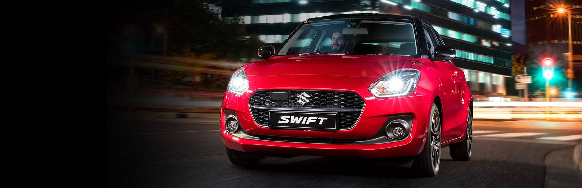 Red suzuki driving in a city at night